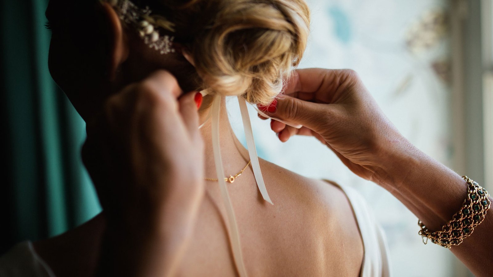 Close-up of a bride having a ribbon tied in her hair on the morning of her wedding