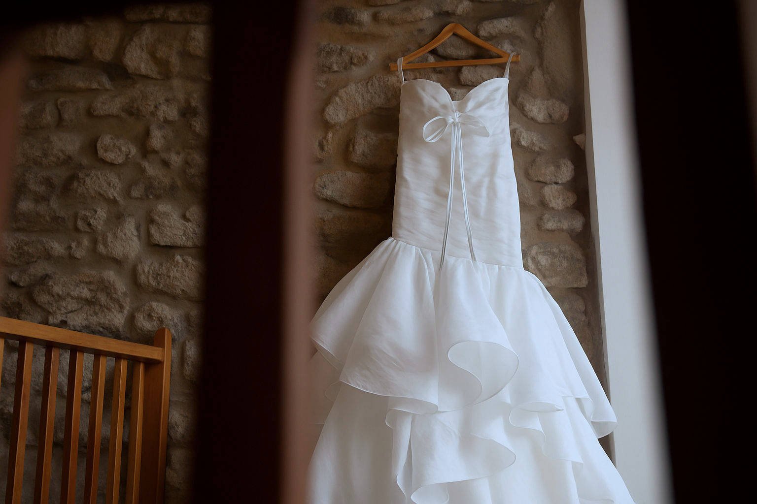 Strapless wedding dress hanging against rustic stone wall at Holmes Mill, Clitheroe